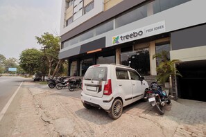 A building with a sign reading 'treebo | PREM TOWER' and a white car parked in front. - Treebo Prem Tower (Haldwani)