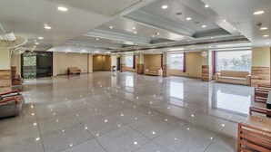 Un hall d’entrée spacieux, doté d’un sol carrelé brillant, de coins salon et de ventilateurs de plafond.