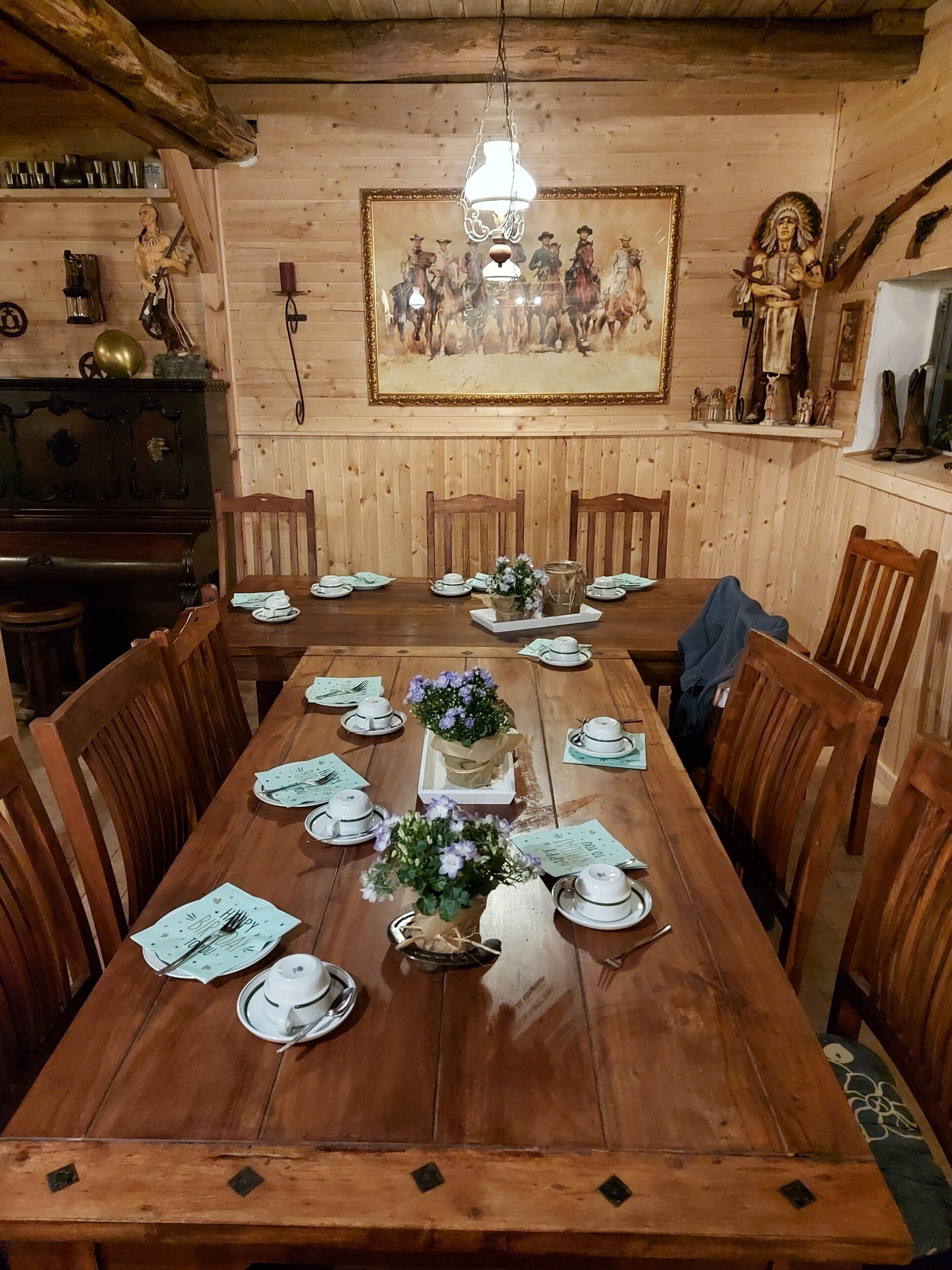 Une salle à manger en bois avec une longue table dressée pour un repas, entourée de chaises.
