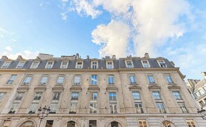 Um edifício de vários andares com arquitetura clássica, apresentando uma fachada simétrica, várias janelas e um telhado plano.