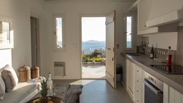 Una cucina con vista sul mare, una zona pranzo con tavolo e sedie, e un divano.