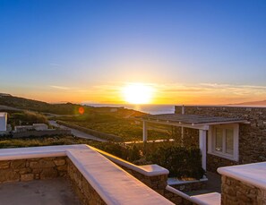Ein Steinhaus mit Blick auf den Sonnenuntergang über dem Meer.