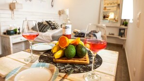 Ein Esstisch mit Früchten, zwei Gläsern Rotwein und einer Spirituosenflasche.