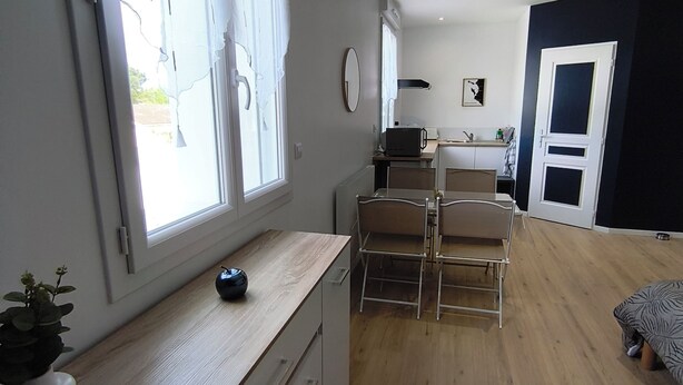 Una cocina moderna con zona de comedor, suelo de madera y un ventanal grande.