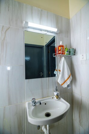 Ein Badezimmer mit einem weißen Waschbecken, einem Spiegel und einem Ablagefach für Toilettenartikel.