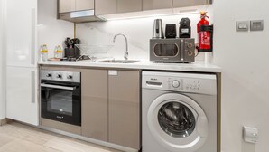 A compact kitchen with a built-in oven, microwave, and washing machine. - Free Housekeeping Visits During Your Stay - Stayshort - Peaceful Studio for 2 in Meydan (Dubai)