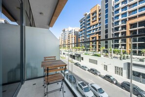 Ein Balkon mit Tisch und Stühlen mit Blick auf eine Straße mit Autos und modernen Gebäuden.