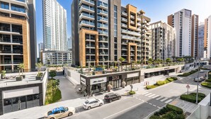 A modern urban hotel with multiple high-rise buildings, a rooftop terrace, and a street view with cars. - Free Housekeeping Visits During Your Stay - Stayshort - Peaceful Studio for 2 in Meydan (Dubai)