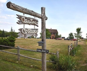 A rustic wooden signpost with 'Cottages' and 'Vacancy' signs, a wooden fence, and a building in the background. - Coastal Maine Escape in Castine – Kayaks, Sunsets & Classic Family Fun (Castine)