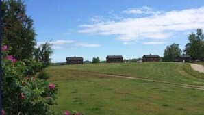 A grassy field with a few buildings in the distance and a clear sky.