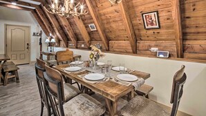 Comedor de madera con techo alto, candelabros y una mesa dispuesta para cuatro comensales.