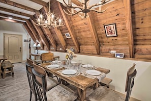 A wooden dining room with a high ceiling, chandeliers, and a table set for four. - Daltun’s Ranch | Hot Tub • Game Room • Firepit (Asheville)