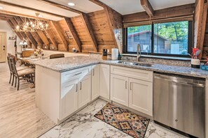 A kitchen with a granite countertop, white cabinets, a stainless steel dishwasher, and a wooden ceiling. - Daltun’s Ranch | Hot Tub • Game Room • Firepit (Asheville)