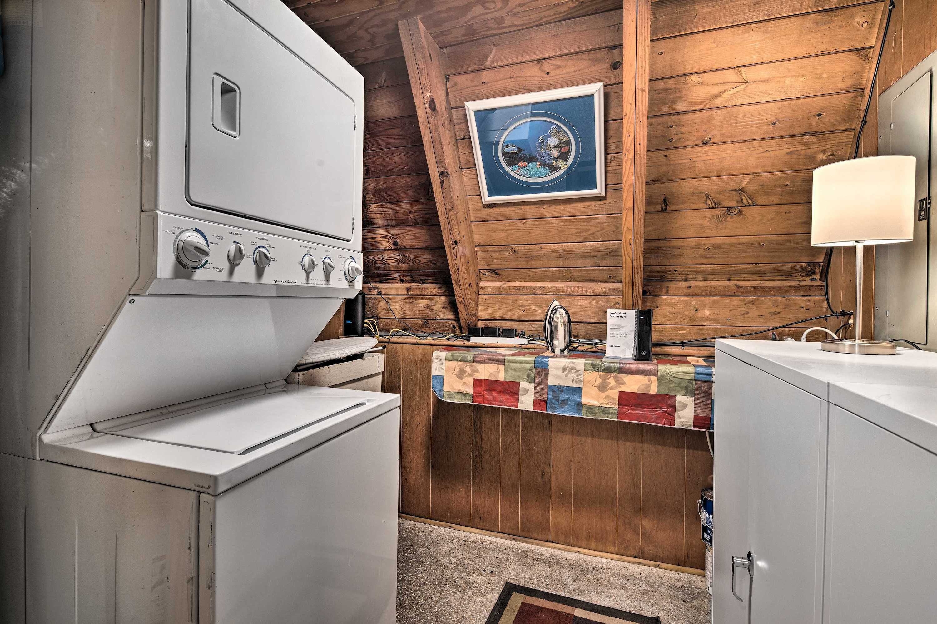 A compact kitchen with a washing machine, a sink, and a wooden ceiling.