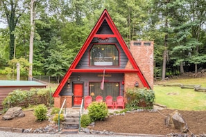 A two-story building with a red and black exterior, a balcony with red chairs, and a sign reading 'The Biltong.' - Daltun’s Ranch | Hot Tub • Game Room • Firepit (Asheville)