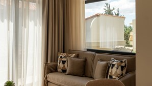 Una sala de estar moderna con un sofá, dos mesas redondas y vistas a través de un ventanal.