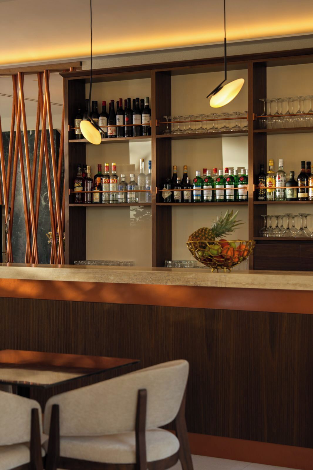 A bar area with shelves of liquor bottles, glasses, and a pineapple centerpiece.