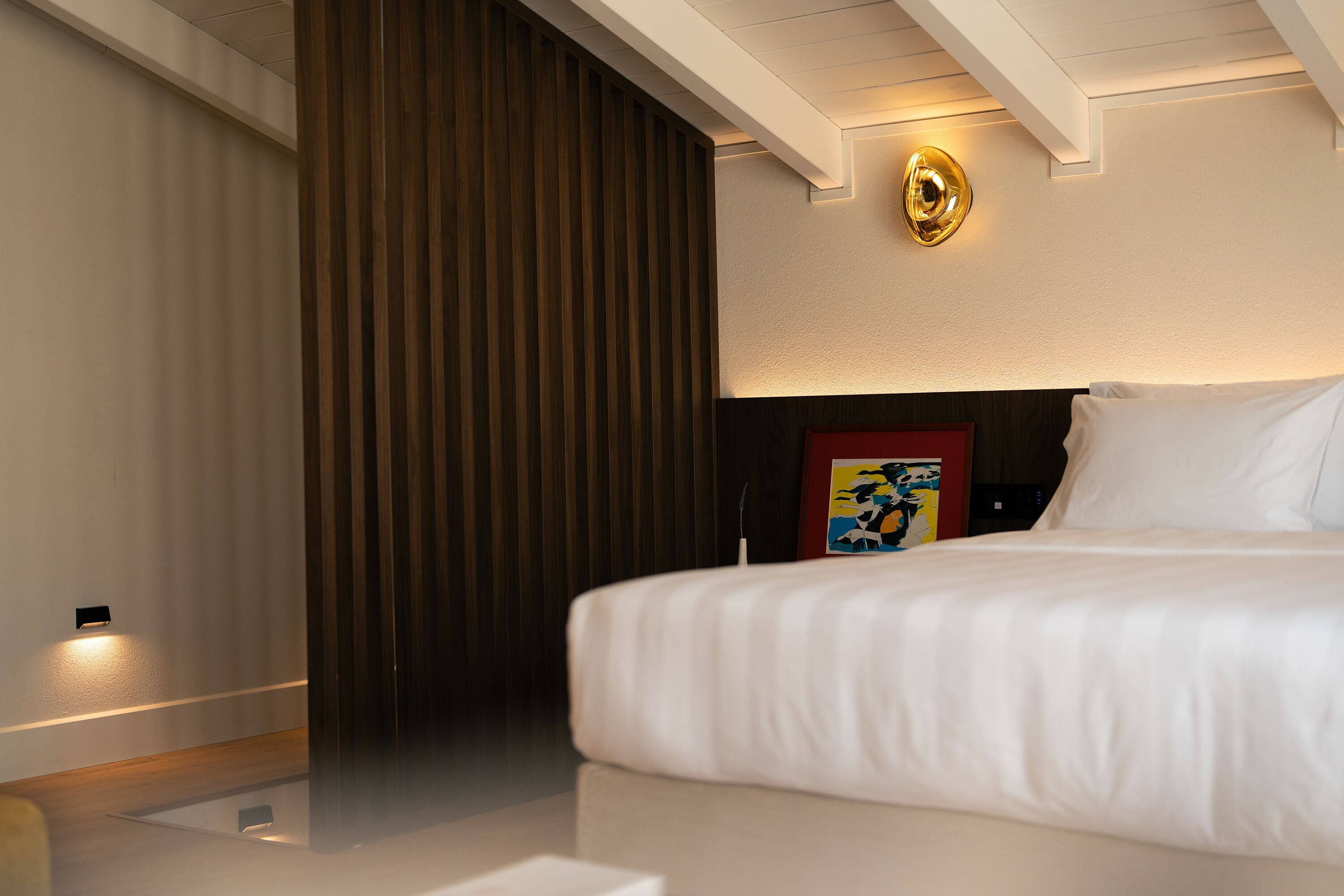 Una habitación de hotel con una cama, un cuadro en la pared y una lámpara en el techo.
