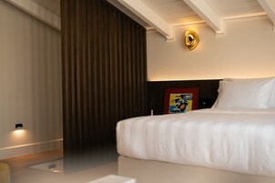 Una habitación de hotel con una cama, un cuadro en la pared y una lámpara en el techo.