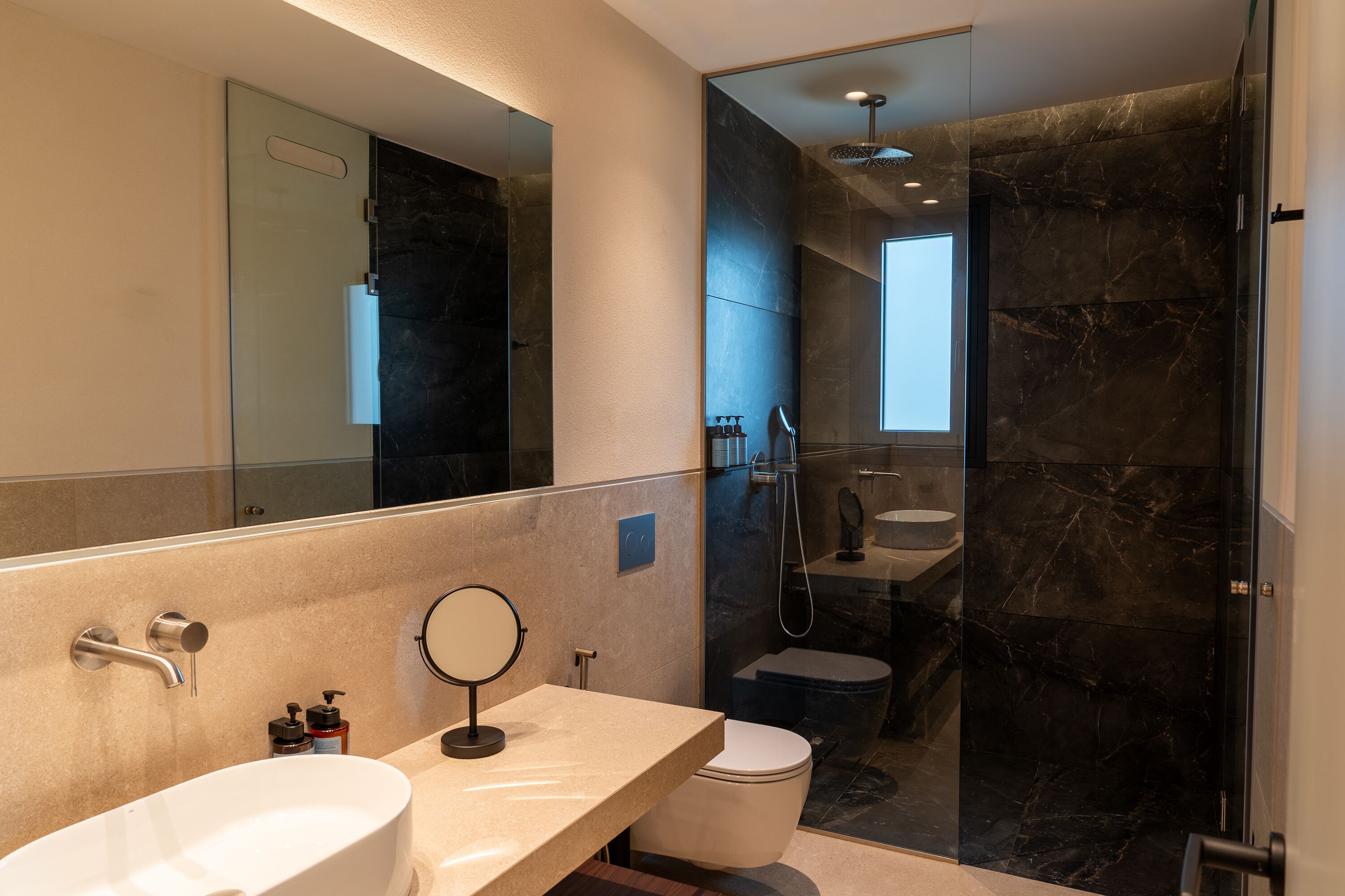 A modern bathroom with a large mirror, a bathtub, a toilet, and a shower area.