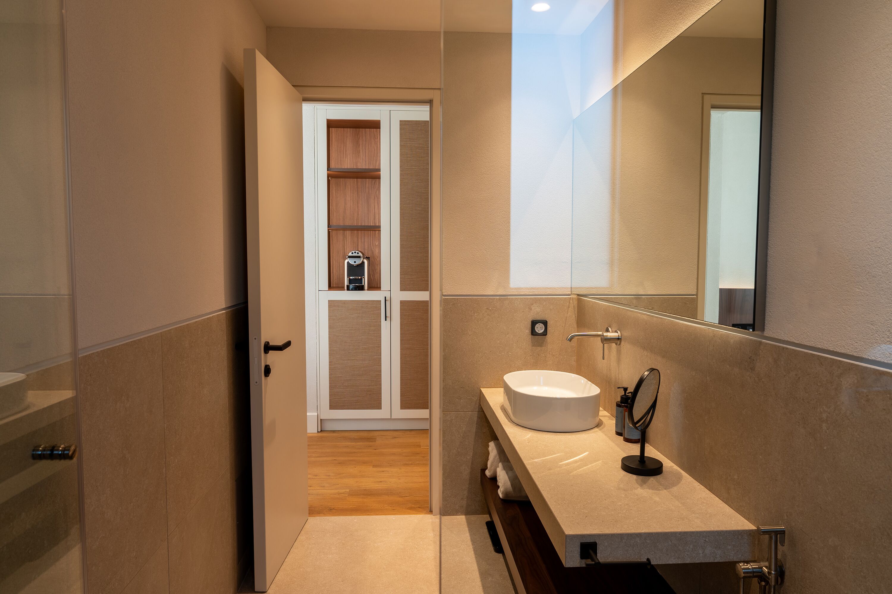A modern bathroom with a large mirror, a sink, and a shower area.