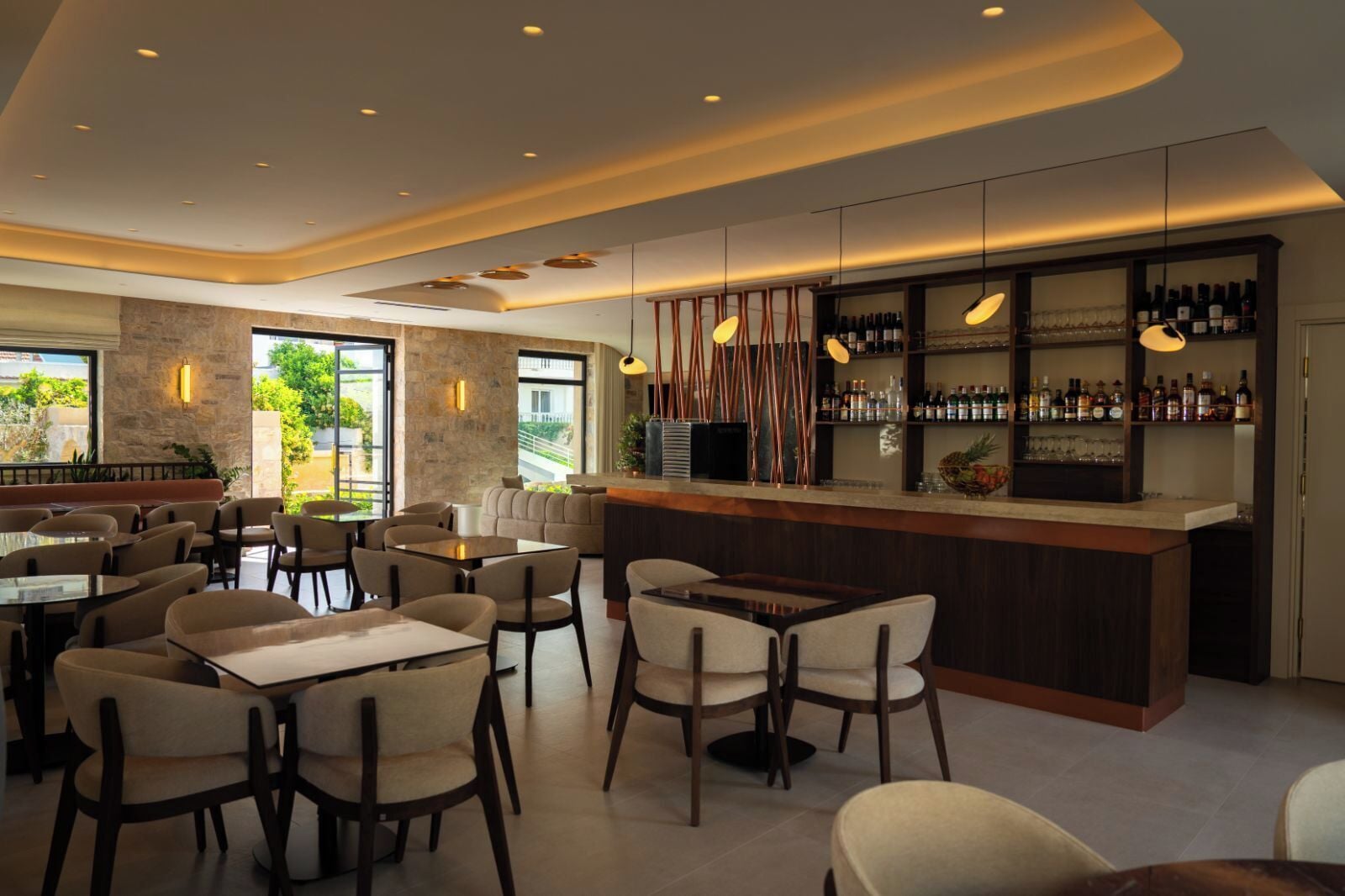Una zona de bar moderna con mostrador, asientos y vistas al exterior.
