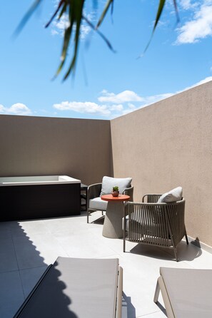Terraço no telhado com área de estar, uma pequena mesa e uma banheira de hidromassagem.