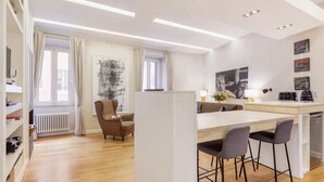 Et moderne køkken med en central ø, barstole og et spiseområde.