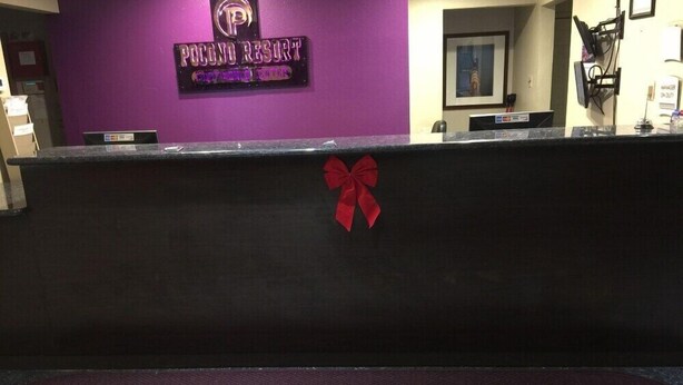 Ein Empfangsschalter im Pocono Resort, mit einer violetten Wand, einer roten Schleife und einem gerahmten Bild über der Theke.