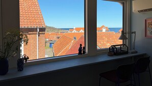 A room with large windows, a desk, a lamp, and a vase with flowers. - Bright apartment near sea and harbour (Allinge-Sandvig)