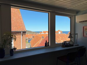 A room with large windows, a desk, a lamp, and a vase with flowers. - Bright apartment near sea and harbour (Allinge-Sandvig)