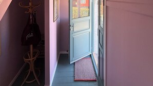 A hallway with a door leading to an outdoor area, a coat rack, and a hanging bag. - Bright apartment near sea and harbour (Allinge-Sandvig)