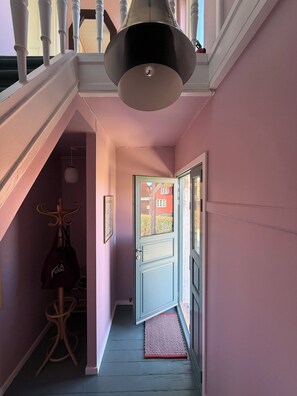 A hallway with a door leading to an outdoor area, a coat rack, and a hanging bag. - Bright apartment near sea and harbour (Allinge-Sandvig)