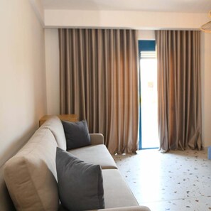 A living room with a sofa, a small table, and a view through a doorway. - Dolanit Hotel Village (Golem)