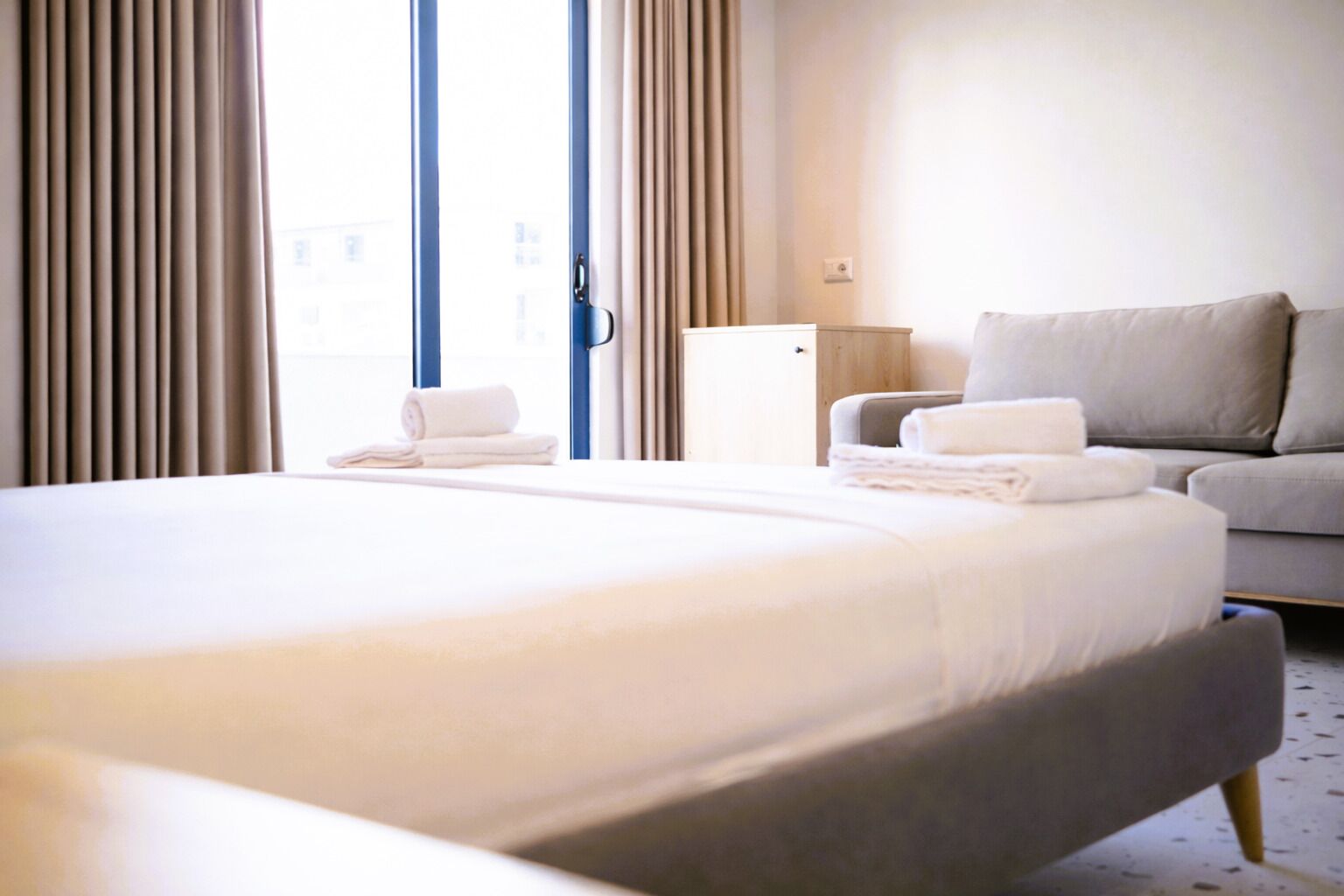 A hotel room with a large bed, a sofa, and a small table.