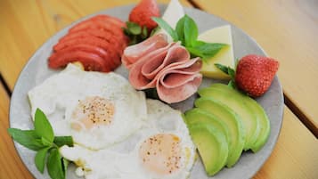 A plate with eggs, ham, strawberries, cheese, and avocado.