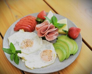 Ein Teller mit Eiern, Schinken, Erdbeeren, Käse und Avocado.
