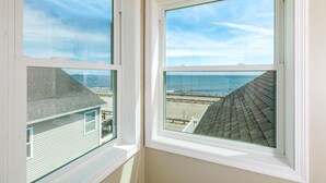 A room with two windows, one with a view of the beach and the other with a view of the ocean. - Oceanfront Apartment w/ 2 Bedroom + den & pool access (Hampton)