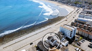 An aerial view of a coastal area with a beach, a road, and buildings. - Oceanfront Apartment w/ 2 Bedroom + den & pool access (Hampton)