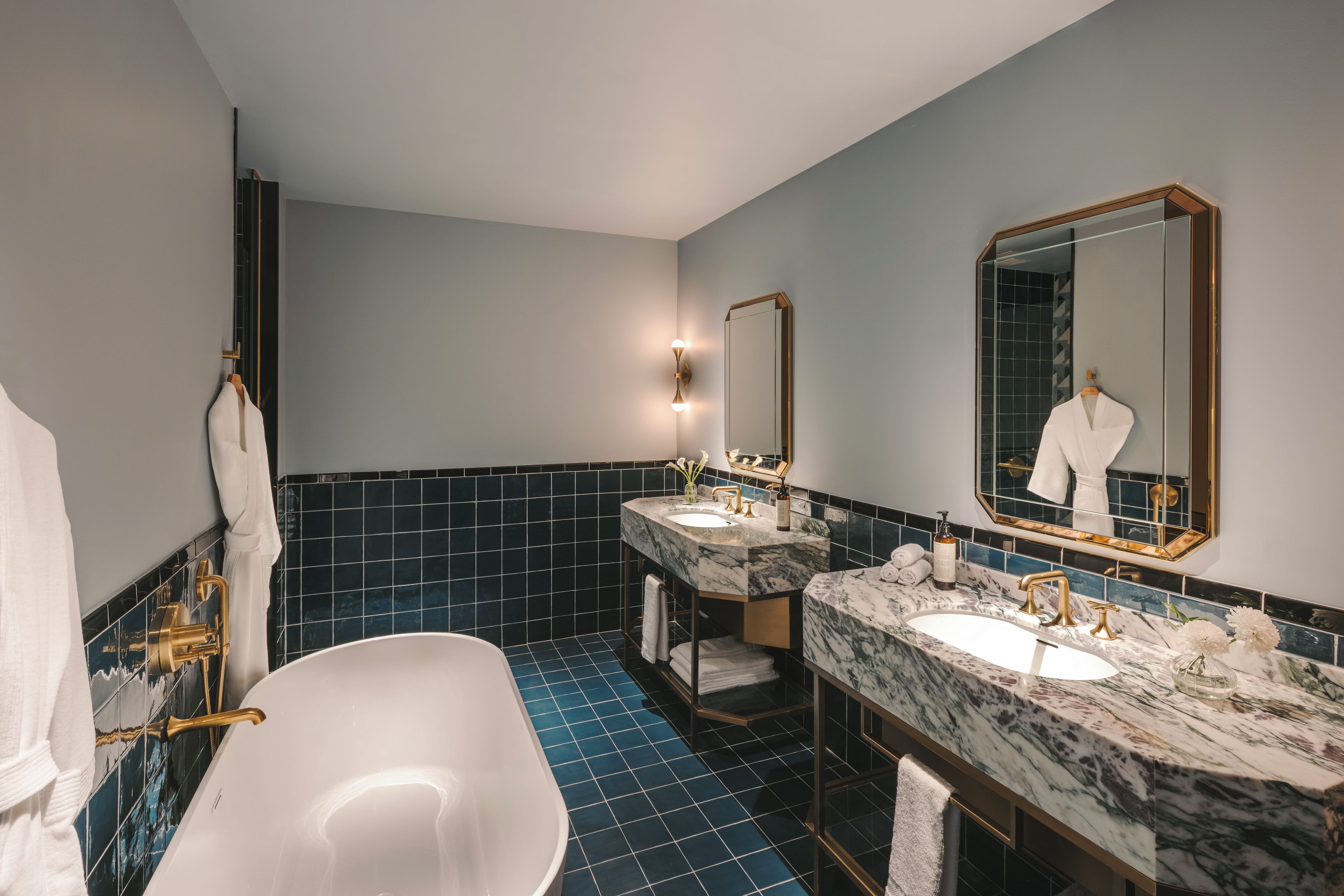 Une salle de bain moderne avec une baignoire, deux lavabos et un grand miroir.