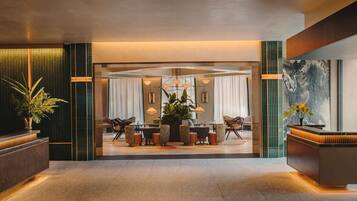 A modern hotel lobby with a reception desk, seating area, and a large window.