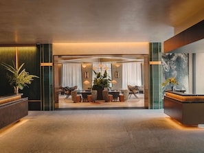 A modern hotel lobby with a reception desk, seating area, and a large window. - Fairmont New Orleans (Opening November 2026) (New Orleans)