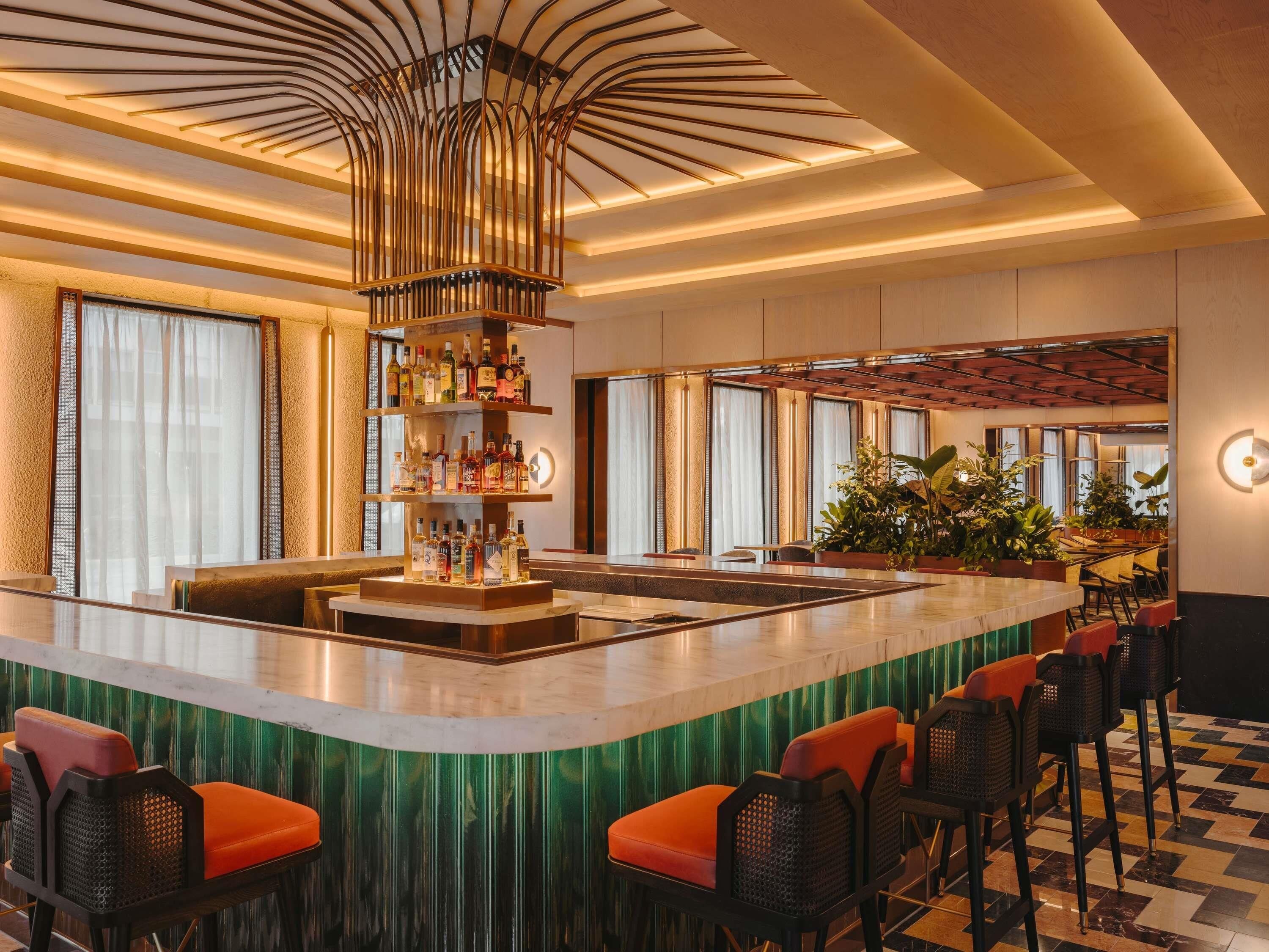 Eine Bar mit Barbedienung, Sitzgelegenheiten und einer dekorativen Decke.