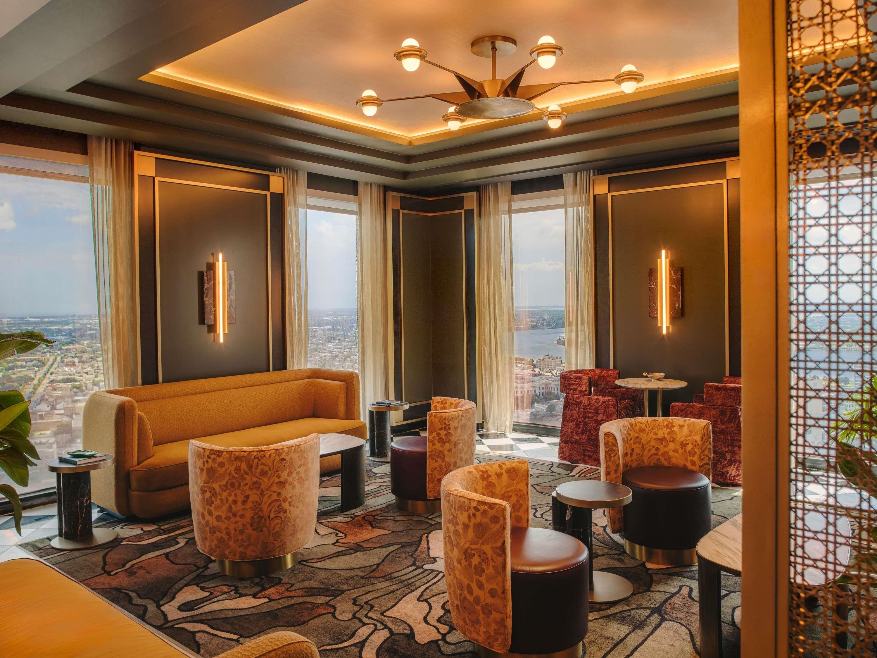 Un salon moderne avec un canapé, des fauteuils à motifs et une vue sur la ville.