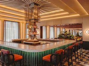 Zona de bar con barra central, asientos y techo decorativo.