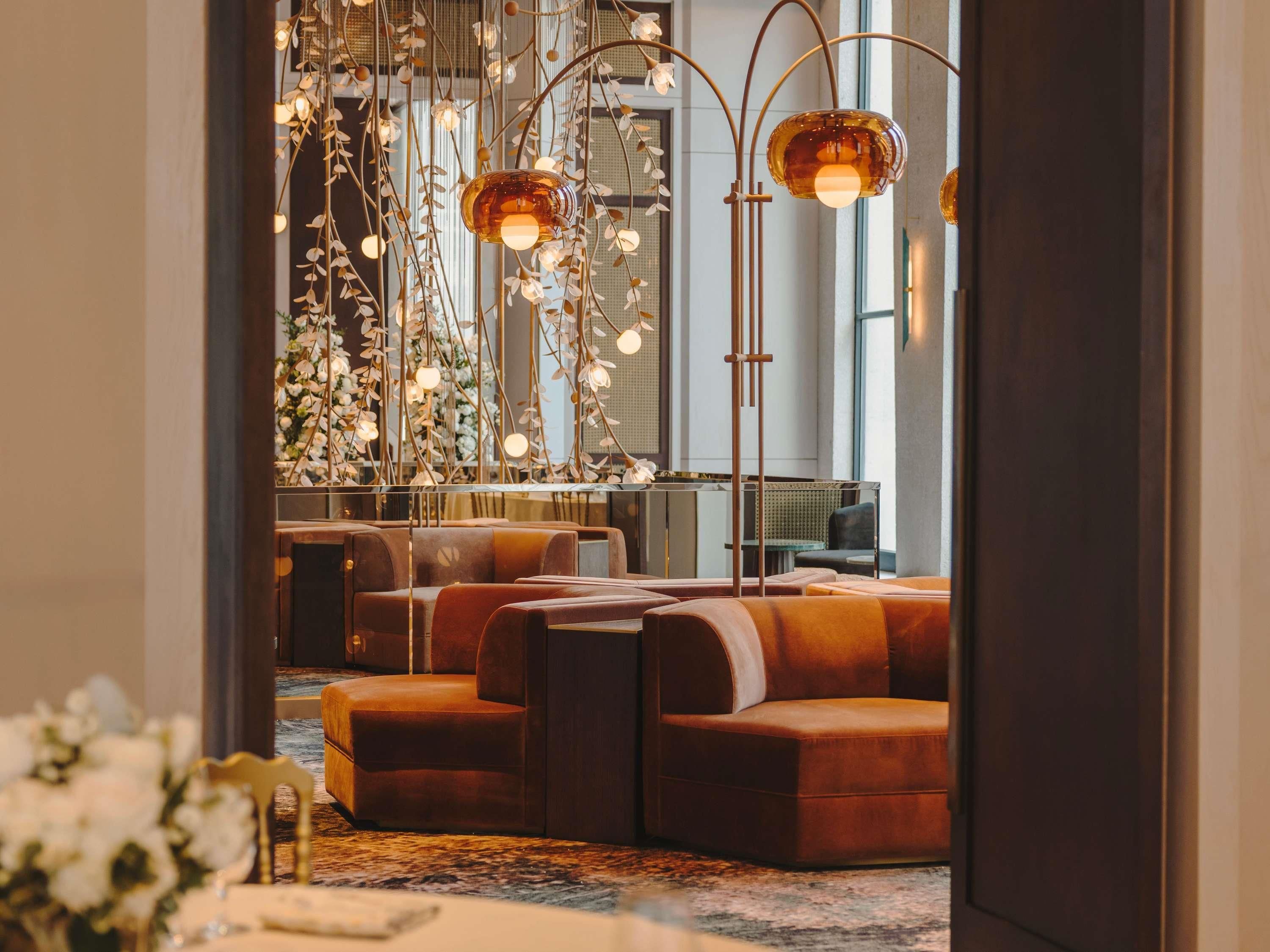 A modern interior with seating areas, a decorative light fixture, and a view of the outdoors.