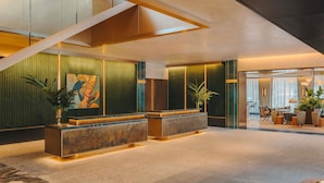 A modern lobby with a reception desk, seating area, and a staircase.