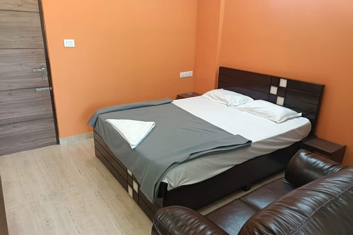 Un dormitorio con cama, mesita de noche, armario de madera y sofá de cuero marrón.
