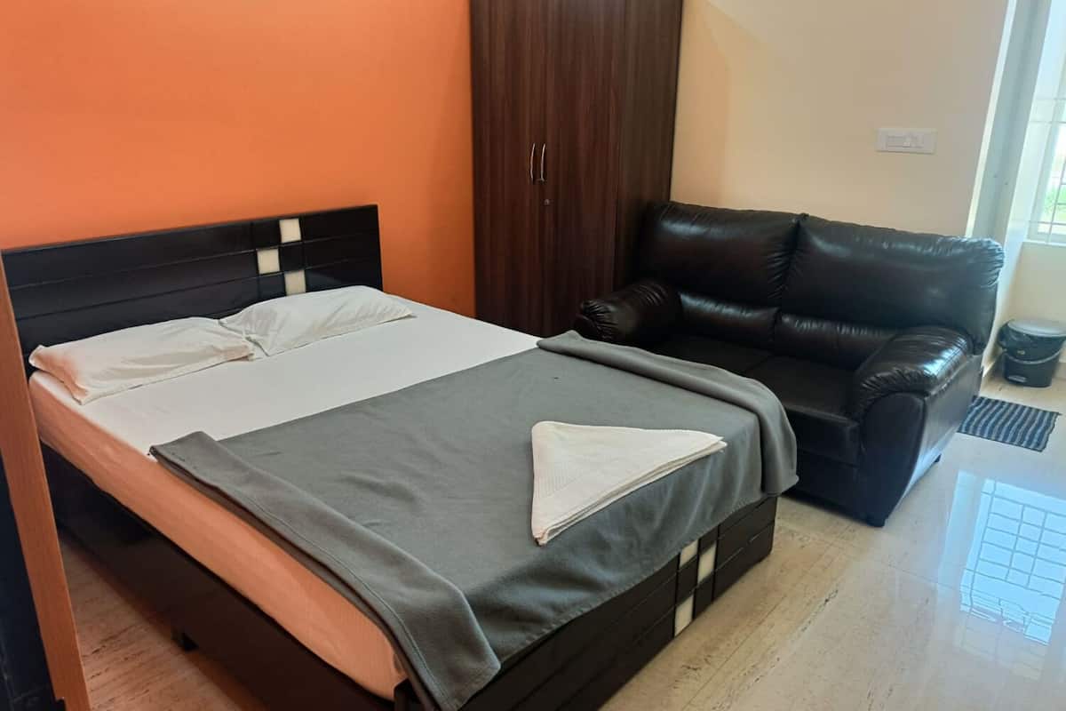Un dormitorio con una cama, un armario marrón oscuro y una butaca de cuero negro.