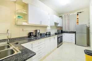 A kitchen with a granite countertop, stainless steel appliances, white cabinets, and a tiled backsplash. - Amboseli home away from home  3-bedroom apartment in Nairobi (Nairobi)